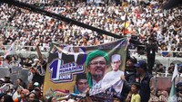 Pendukung AMIN membawa atribut dukungan seperti poster dan spanduk. 
