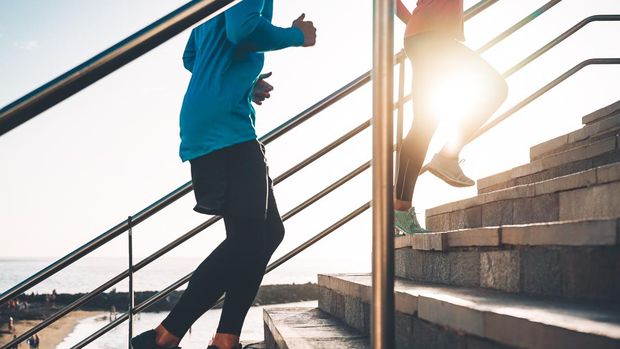 1134986460 View of runners legs training outdoor - Young couple doing a workout session on stairs next the beach at sunset - Healthy people, jogging and sport lifestyle concept