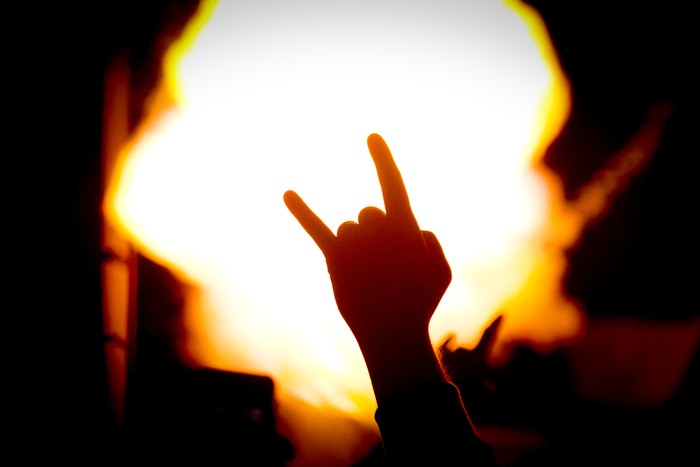 1464855874 silhouette of hand gesturing in front of fire during a concert