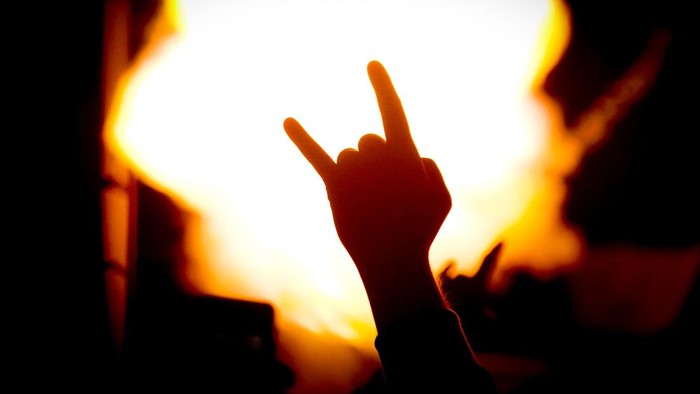 silhouette of hand gesturing in front of fire during a concert