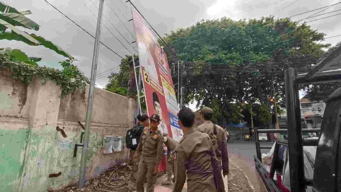 Bawaslu dan Satpol PP menertibkan APK di jalan protokol Banyuwangi saat masa tenang Pemilu 2024.