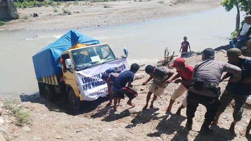 Warga menarik truk pengangkut logistik pemilu yang mati saat hendak melintas di Sungai Kapsali, Kabupaten Kupang, NTT. (Foto: Istimewa)