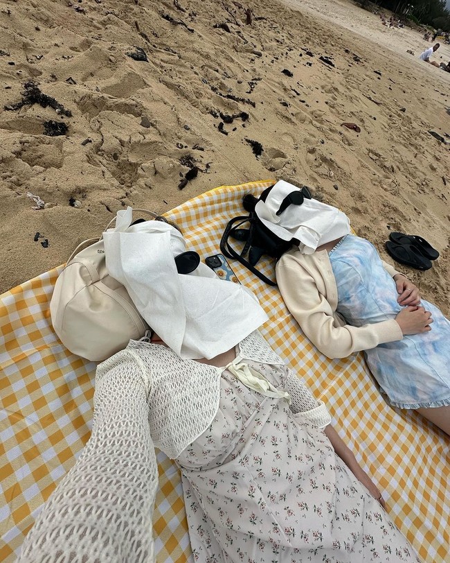 Pantai menjadi destinasi favoritnya. Dalam salah satu foto, Eunbi dan Minju berpose lucu saat berjemur. Wajah keduanya ditutupi dengan beberapa helai tisu hingga tidak terlihat, ditambah dengan kacamata hitam. Foto: dok. Instagram @silver_rain.__