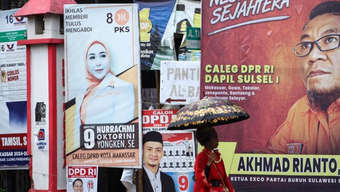 Warga melintas di depan alat peraga kampanye (APK) di Makassar, Sulawesi Selatan, Senin (12/2/2024). Memasuki hari kedua masa tenang Pemilu 2024 sejumlah APK di beberapa titik di daerah itu belum ditertibkan. ANTARA FOTO/Arnas Padda/foc.