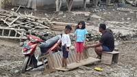 Anak kecil bermain di antara lumpur yang terbawa oleh banjir