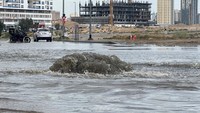 Sebuah mobil dan sepeda motor melewati jalan yang banjir pasca hujan badai lebat, di Dubai.  