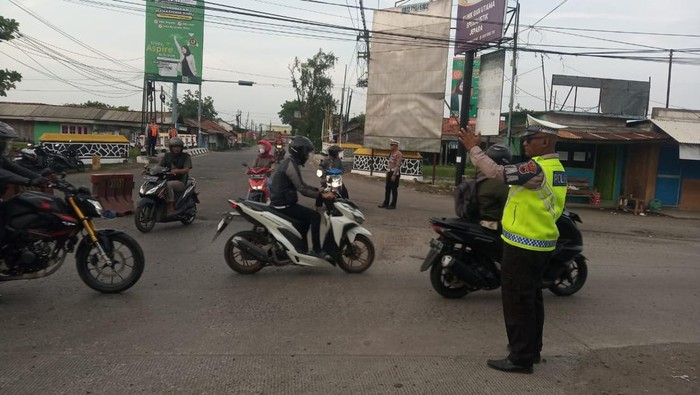 Anggota Satlantas Polres Demak mengatur lalu lintas di simpang 3 Trengguli, Wonosalam, Selasa (13/2/2024).