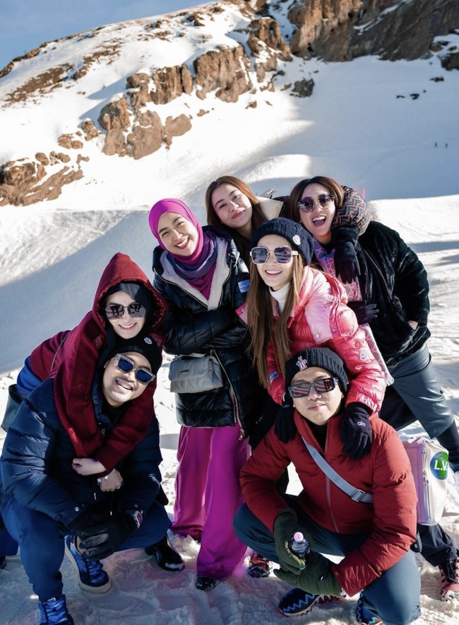 Beda lagi gaya sewaktu ke Swiss. Busana berwarna fuchsia yang dibungkus puffer jacket hitam menemani. (Foto: Instagram/@riaricis1795)