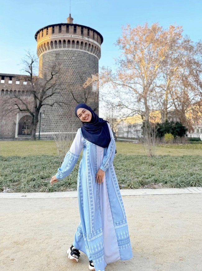 Milan, Italia, menjadi destinasi pertama yang dikunjunginya bersama rekannya sesama figur publik di Benua Biru. Tunik dress bernuansa biru yang dipadu hijab senada menjadi andalan ibu satu anak ini. (Foto: Instagram/@riaricis1795)