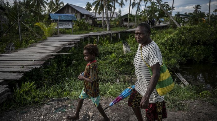 Seorang mama Papua berjalan bersama anaknya di Kampung Saw, Distrik Agats, Kabupaten Asmat, Papua Selatan, Selasa (13/2/2024). Kabupaten Asmat memiliki 224 kampung atau setara tingkat kelurahan yang berdiri di atas tanah berlumpur dan rawa serta memiliki sarana jalan dari papan kayu. ANTARA FOTO/Aprillio Akbar/Spt.