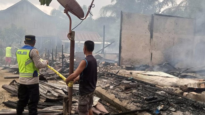 Petugas memasang garis polisi di lokasi rumah yang dibakar suami di Mura.
