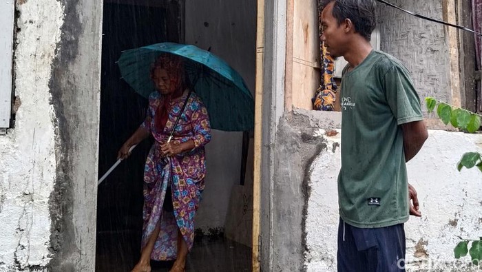 Wafi dan Ibunya membersihkan rumah dari air hujan yang masuk bagian depan imbas atap diterjang angin kencang.
