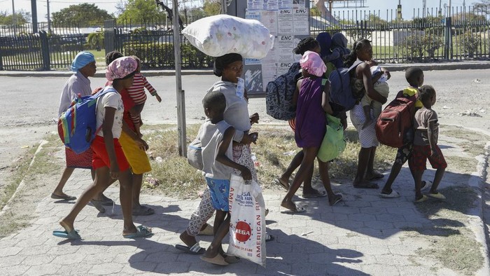 Warga Haiti Kabur dari Rumah Takut Serangan Geng Bersenjata Children and their guardians gather outside a police station after they fled their homes in Cite Soleil due to gang violence, in Port-au-Prince, Haiti, Monday, Feb. 12, 2024. (AP Photo/Odelyn Joseph)