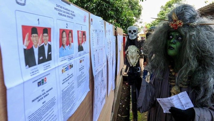 Slamet Suwito menggunakan kostum tokoh Mak Lampir melihat daftar nama capres-cawapres sebelum melakukan pencoblosan di TPS 07 Wonorekso, Alasmalang, Banyuwangi, Jawa Timur, Rabu (14/2/2024). Penggunaan kostum tokoh Mak Lampir untuk memeriahkan pesta demokrasi Pemilu 2024. ANTARA FOTO/Budi Candra Setya/tom.