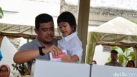Bobby Nasution menggendong putri sulungnya ketika memasukkan surat suara di kotak suara di TPS (Goklas Wisely/detikSumut)