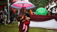 Sebagian warga datang dengan memakai payung agar terhindar dari guyuran hujan.