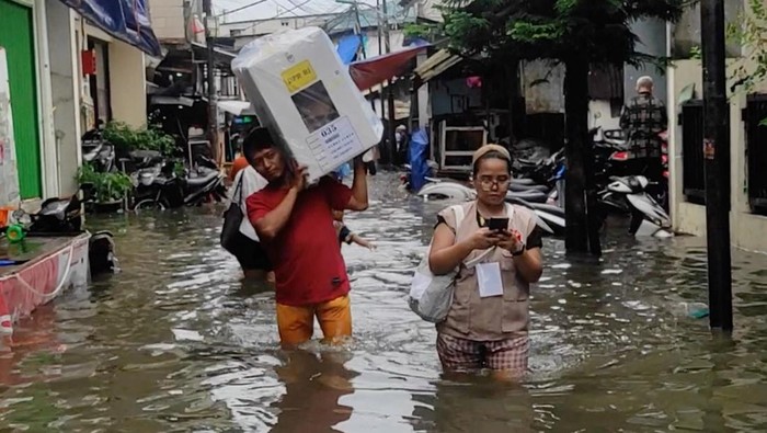 People walk through flood water on the day of general elections, in Jakarta, Indonesia, February 14, 2024, in this picture obtained from social media. Adi Utama Putra/via REUTERS  THIS IMAGE HAS BEEN SUPPLIED BY A THIRD PARTY. MANDATORY CREDIT. NO RESALES. NO ARCHIVES.
