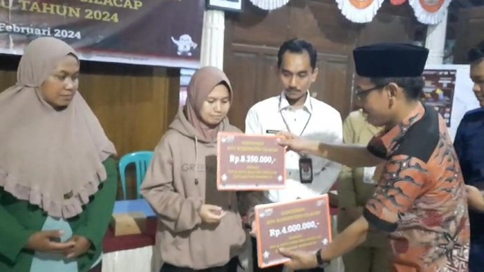 Kepala Divisi Sumber Daya Manusia (SDM) KPU Cilacap, M. Mughni menyerahkan santunan kepada petugas KPPS yang mengalami keracunan di balai Desa Majingklak, Kecamatan Wanareja, Kabupaten Cilacap, Selasa (13/2/2024) malam.
