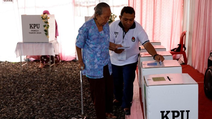 An electoral worker helps an elderly woman at a polling station during general elections, in Surakarta, Central Java province, Indonesia, February 14, 2024. REUTERS/Willy Kurniawan