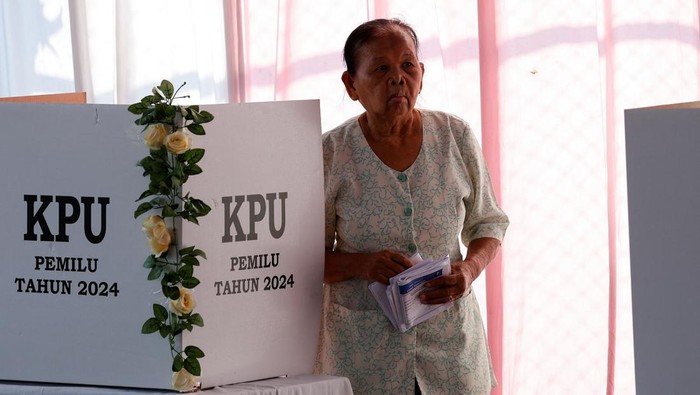 An electoral worker helps an elderly woman at a polling station during general elections, in Surakarta, Central Java province, Indonesia, February 14, 2024. REUTERS/Willy Kurniawan