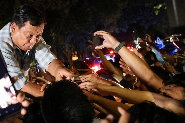 Indonesias Defence Minister and presidential candidate Prabowo Subianto accompanied by Indonesias vice president candidate Gibran Rakabuming Raka, who is the eldest son of Indonesian President Joko Widodo and current Mayor of Surakarta, greet supporters from a car in Jakarta, Indonesia February 14, 2024. REUTERS/Ajeng Dinar Ulfiana