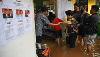 Seorang petugas membantu warga yang akan memberikan suara pada Pemilu 2024 saat banjir yang menggenang di TPS 028 Jelambar, Jakarta Barat, Rabu (14/2/2024).