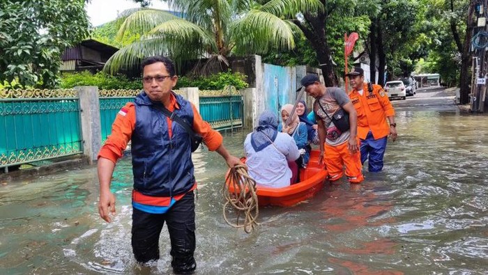 Petugas BPBD DKI Jakarta menjemput warga yang akan nyoblos di TPS wilayah Kembangan, Jakarta Barat dengan perahu karet karena banjir.