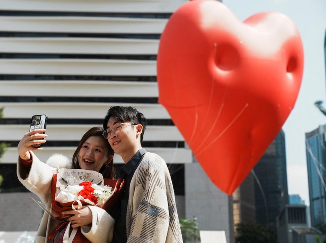 Visitors pose for pictures with a giant inflatable heart called Chubby Hearts, an installation by designer Anya Hindmarch, on Valentines Day in Hong Kong, China February 14, 2024. REUTERS/Lam Yik