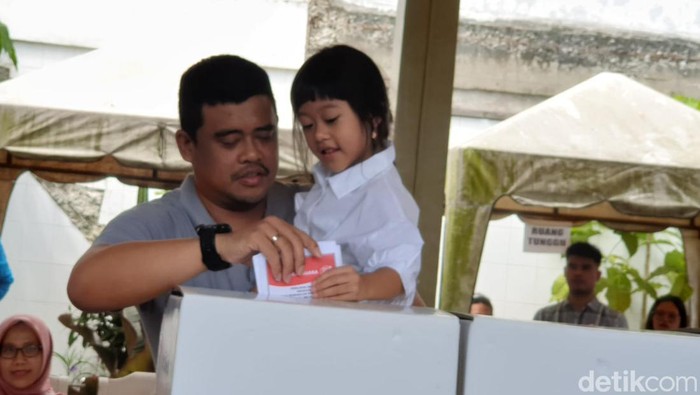 Wali Kota Medan Bobby Nasution menggendong putrinya saat hendak memasukkan surat suara ke dalam kotak suara di TPS 34 Kompleks Perumahan Tasbih 1, Kelurahan Asam Kumbang, Kecamatan Medan Selayang, Kota Medan. (Goklas Wisely/detikSumut)
