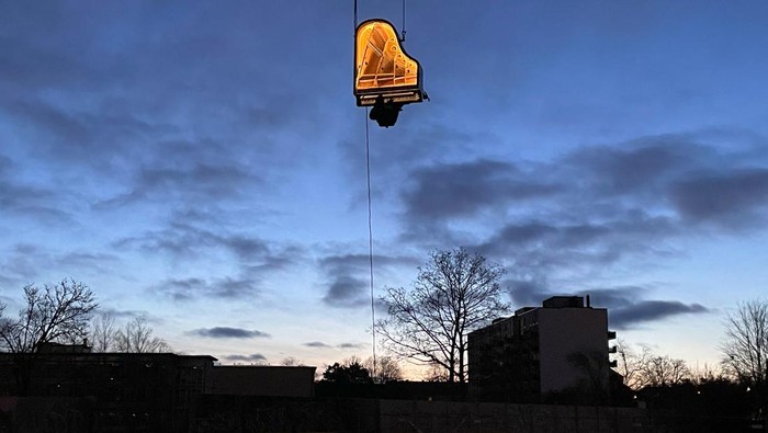 Swiss artist Alain Roche plays the piano hanging from a crane during a concert in Munich, Germany, February 5, 2024.     REUTERS/Louisa Off     TPX IMAGES OF THE DAY