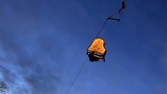 Swiss artist Alain Roche plays the piano hanging from a crane during a concert in Munich, Germany, February 5, 2024.     REUTERS/Louisa Off     TPX IMAGES OF THE DAY