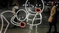 Orang-orang melewati dekorasi lampu saat Hari Valentine di Tirana, Albania, 14 Februari 2024. REUTERS/Florion Goga