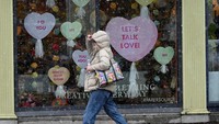 Pejalan kaki berjalan melewati pajangan Hari Valentine di toko alat tulis Paper Source saat badai musim dingin yang bergerak cepat diperkirakan melanda Timur Laut AS, di Wellesley, Massachusetts, AS 13 Februari 2024. REUTERS/Ken McGagh