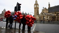 Orang-orang yang membawa balon hati berjalan di dekat Gedung Parlemen pada Hari Valentine, di London, Inggris, 14 Februari 2024. REUTERS/Hannah McKay