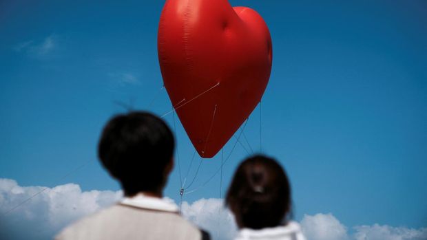 Visitors look at a giant inflatable heart called 