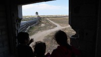Anak-anak pengungsi Palestina melihat tembok perbatasan Gaza.