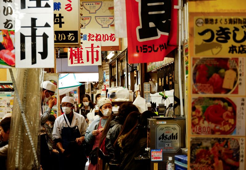 An employee of a seafood restaurant holds a placard displaying the menu to attract customers at Tsukiji Outer Market in Tokyo, Japan February 15, 2024.  REUTERS/Issei Kato