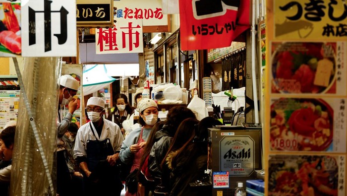 An employee of a seafood restaurant holds a placard displaying the menu to attract customers at Tsukiji Outer Market in Tokyo, Japan February 15, 2024.  REUTERS/Issei Kato