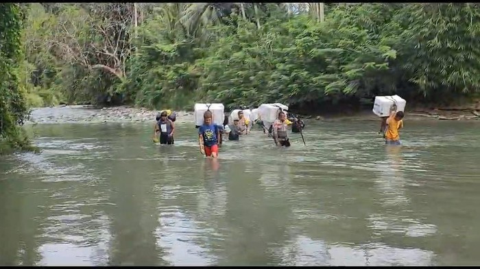 Polisi dan penyelenggara Pemilu di Banggai membawa kotak dan surat suara ke PPK lewati sungai.
