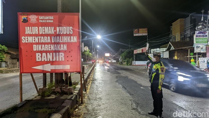 Pengumuman penutupan ruas Jalan Pantura Demak imbas banjir. Tampak polisi mengatur lalin di Simpang Trengguli, Wonosalam, Demak, Jumat (16/2/2024).