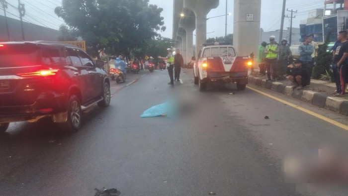 Polisi dan warga saat mengevakuasi korban kecelakaan di Palembang.