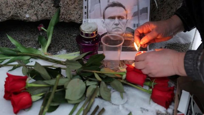 A person lights a candle next to a portrait of Russian opposition leader Alexei Navalny at the monument to the victims of political repression following Navalnys death, in Saint Petersburg, Russia, February 16, 2024. REUTERS/Stringer Purchase Licensing Rights