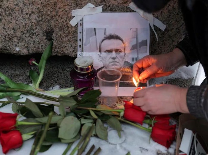 A person lights a candle next to a portrait of Russian opposition leader Alexei Navalny at the monument to the victims of political repression following Navalnys death, in Saint Petersburg, Russia, February 16, 2024. REUTERS/Stringer Purchase Licensing Rights