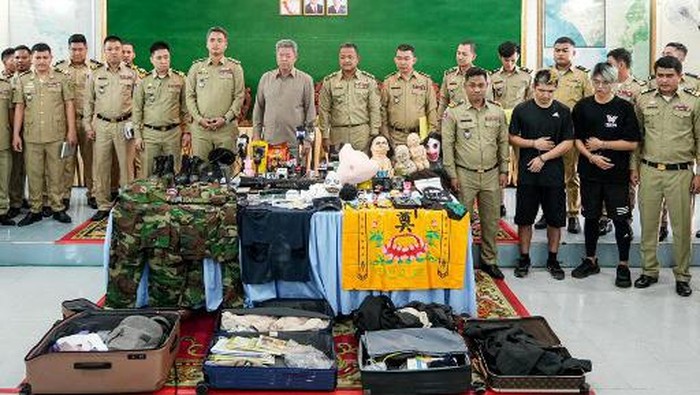 This handout photo taken and released on February 15, 2024 by the Preah Sihanouk Provincial Administration shows Taiwanese men Chen Neng-Chuan (3rd R) and Lu Tsu-hsin (2nd R) standing with police during a press conference in Preah Sihanouk province, after they were arrested for streaming video of a fake kidnapping. Two Taiwanese men have been sentenced to two years in jail each after they staged a fake kidnapping from a Cambodian seaside resort and posted video of it online, a court said on February 16. (Photo by Handout / Preah Sihanouk Provincial Administration / AFP) / -----EDITORS NOTE --- RESTRICTED TO EDITORIAL USE - MANDATORY CREDIT 