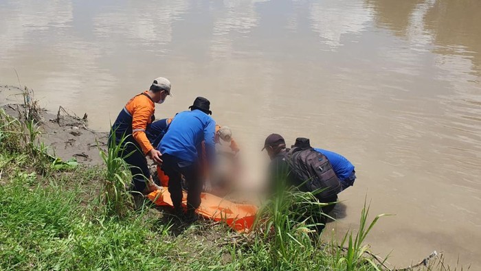 Petugas mengevakuasi mayat pria tanpa identitas yang ditemukan mengambang di aliran Sungai Serayu, Desa Kembangan, Kecamatan Bukateja, Kabupaten Purbalingga, dalam kondisi terikat tali dan dibebani balok beton, Minggu (18/2/2024) pagi.