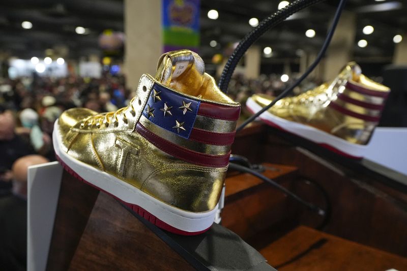 Donald Trump memegang sneakers berwarna emas di Sneaker Con Philadelphia, sebuah acara yang populer di kalangan kolektor sepatu kets, di Philadelphia, Sabtu, 17 Februari 2024.