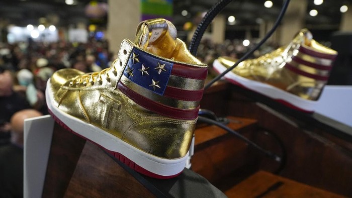 Donald Trump memegang sneakers berwarna emas di Sneaker Con Philadelphia, sebuah acara yang populer di kalangan kolektor sepatu kets, di Philadelphia, Sabtu, 17 Februari 2024.