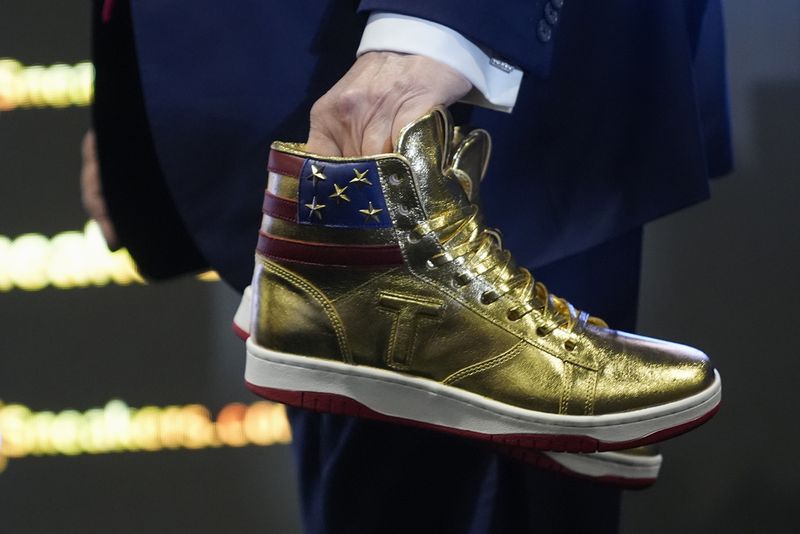 Donald Trump memegang sneakers berwarna emas di Sneaker Con Philadelphia, sebuah acara yang populer di kalangan kolektor sepatu kets, di Philadelphia, Sabtu, 17 Februari 2024.