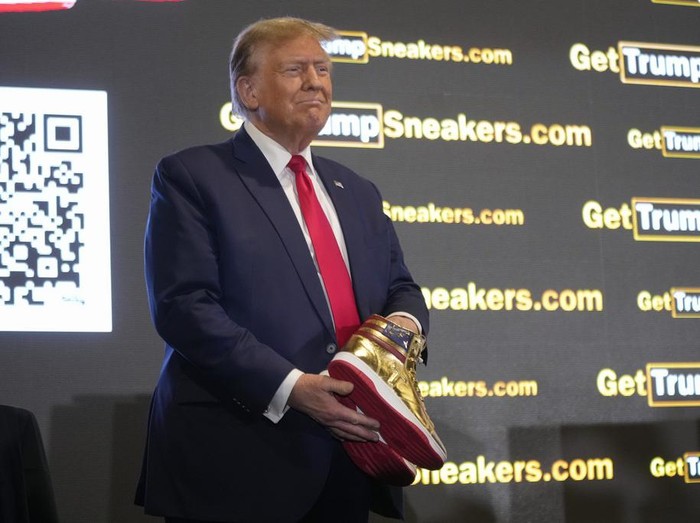 Donald Trump memegang sneakers berwarna emas di Sneaker Con Philadelphia, sebuah acara yang populer di kalangan kolektor sepatu kets, di Philadelphia, Sabtu, 17 Februari 2024.
