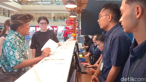 Turis asing membayar pungutan sebesar Rp 150 ribu secara tunai di loket dekat lobi Bandara Internasional I Gusti Ngurah Rai, Minggu (18/2/2024).